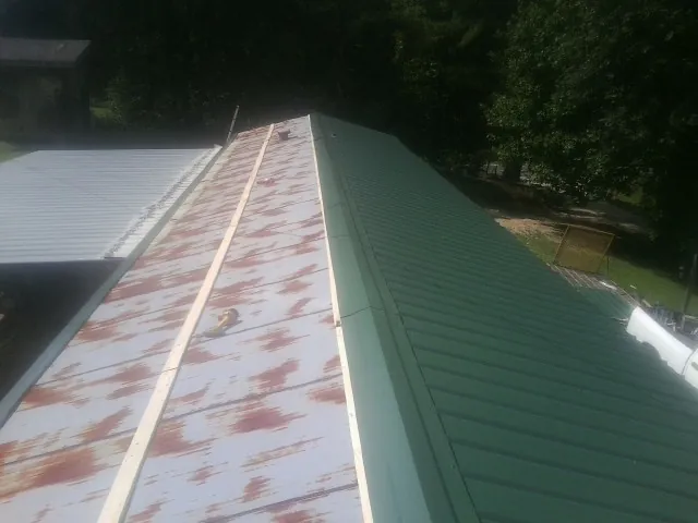 Old rusted panels beside newly installed green metal roofing — Wind Damage Roof Repair by Roofing Brothers in Roseville