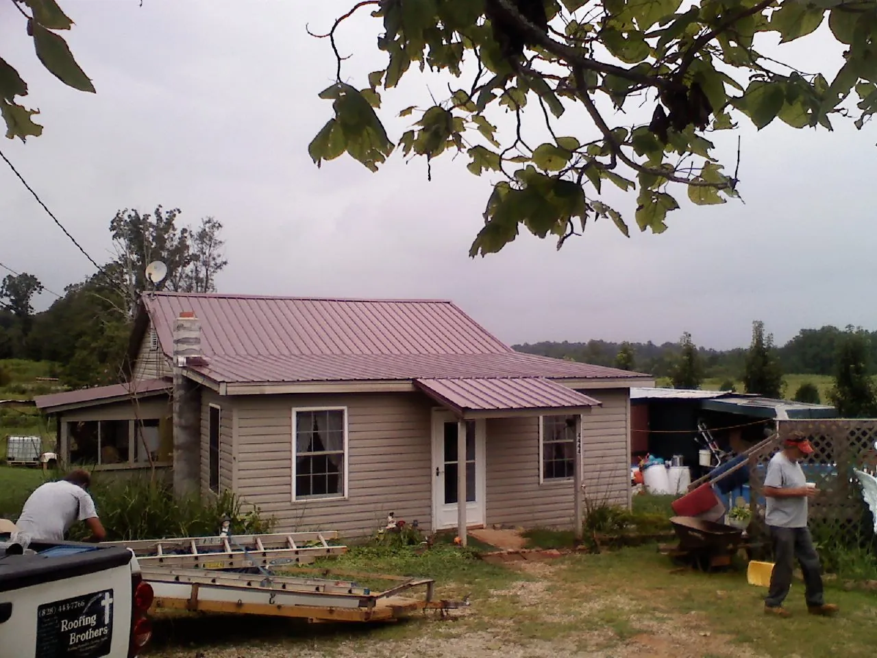 Crew finishing a mauve metal roof on a small farmhouse in Roseville