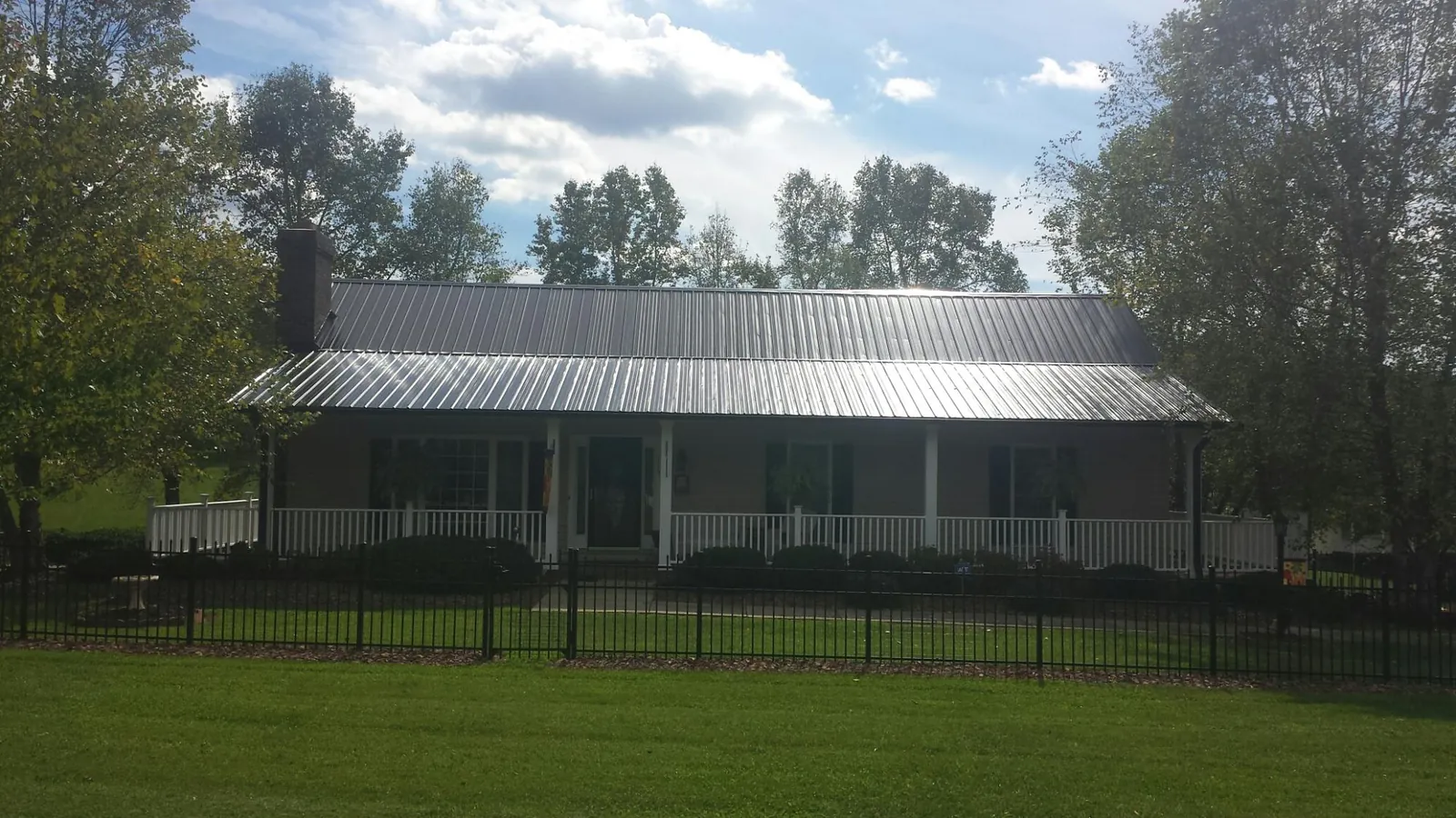 Gray metal roof on a brick ranch with a full width front porch — Gutter Guard Installation work by our crew in Roseville
